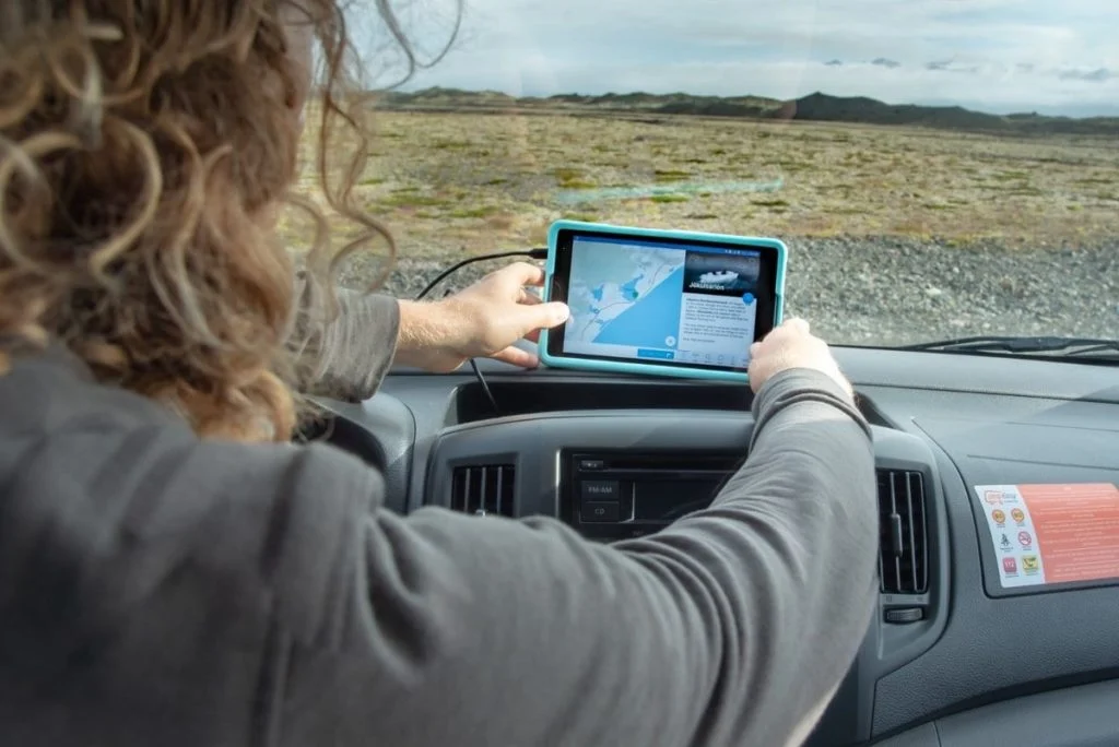 A person mounting a rugged tablet with a navigation map on a car dashboard